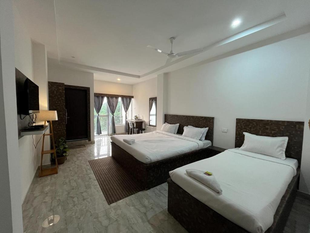 HatikhuliSneha Bhawan Kaziranga的有两张床和一台电视的酒店房间