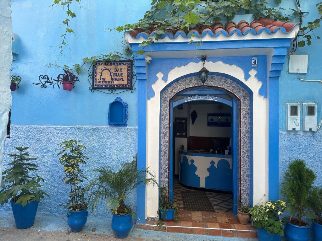a blue building with an archway with potted plants at Dar Bleu Pearl in Chefchaouen