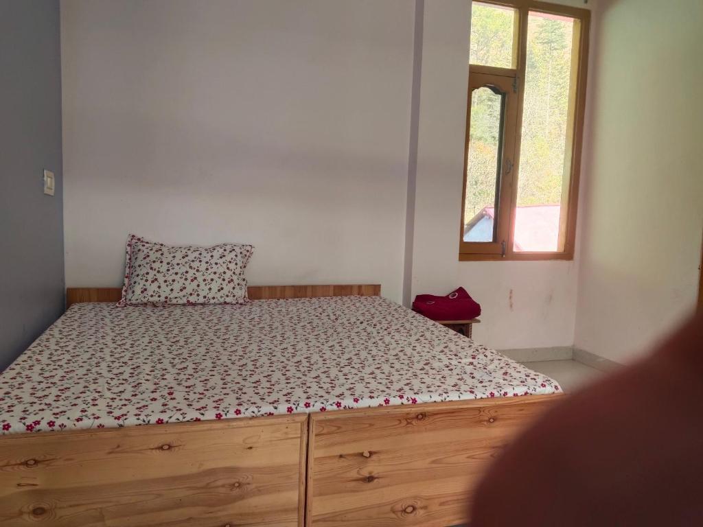 una camera da letto con un letto con un cuscino e una finestra di Mayaloka cafe & stays a Kasol