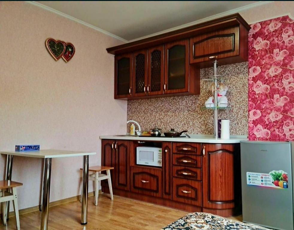 Una cocina con armarios de madera, una mesa y un fregadero. en Квартира-Студія, en Sumy