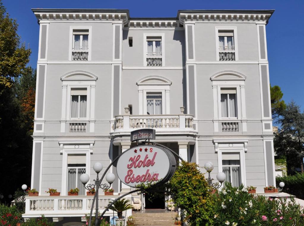 un bâtiment blanc avec un panneau devant lui dans l'établissement Esedra Hotel, à Rimini