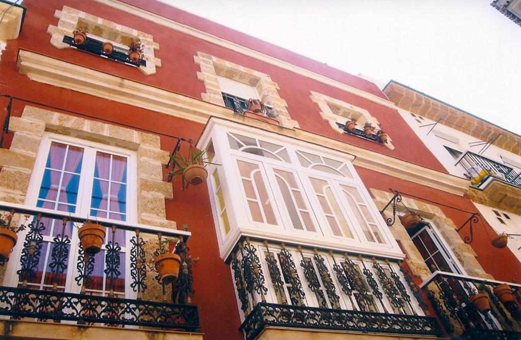 un edificio rojo con ventanas y balcones blancos en Dormir en Cádiz, en Cádiz