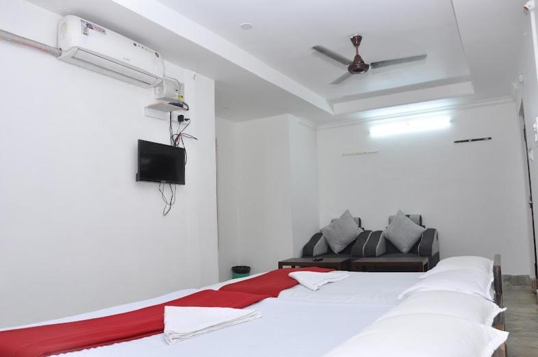 Una habitación blanca con una cama y un sofá. en Sri Raghavendra Inn, en Kākināda