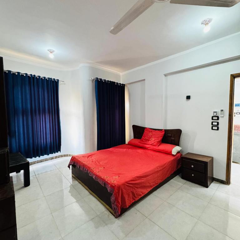 a bedroom with a red bed and a mirror at Memnoun house in Luxor