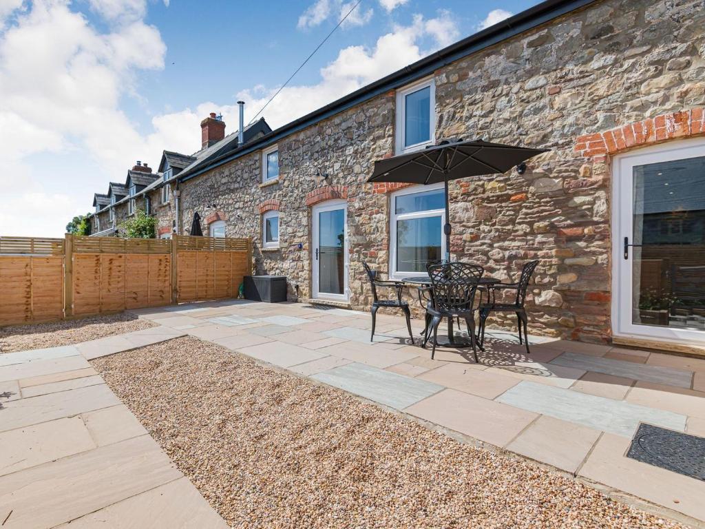 a patio with a table and chairs and an umbrella at The Stables - Cottage in Bryngwyn