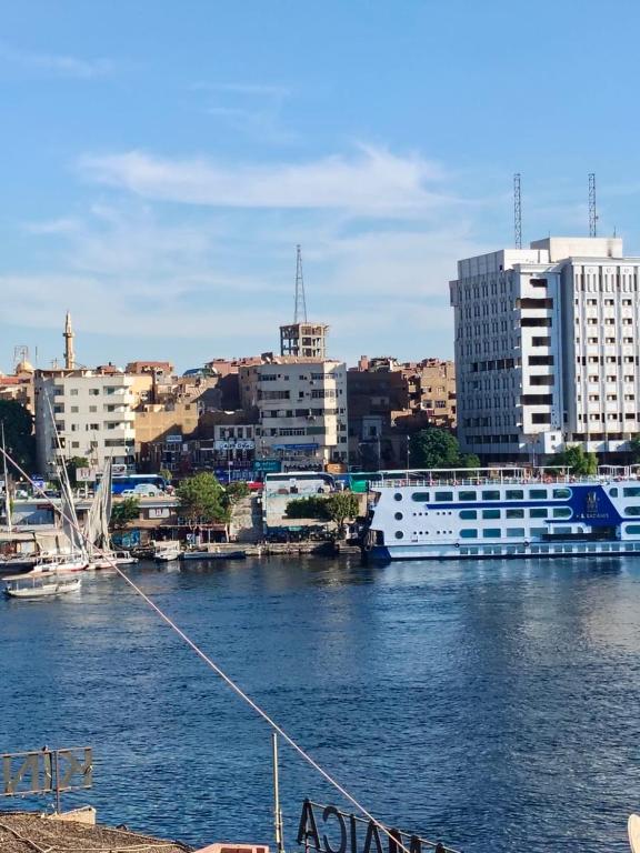 a cruise ship docked in a harbor with buildings at Mostafa Jamaica guesthouse in Aswan