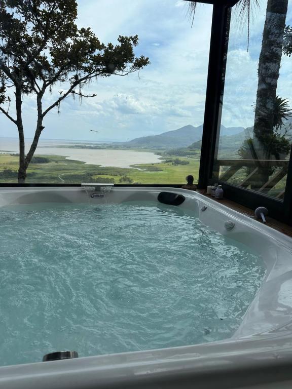 a jacuzzi tub with a view of the water at Chalé Bela Vista - Três Cachoeiras in Três Cachoeiras