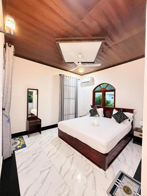 a bedroom with a large bed and a wooden ceiling at New Star Villa in Bentota