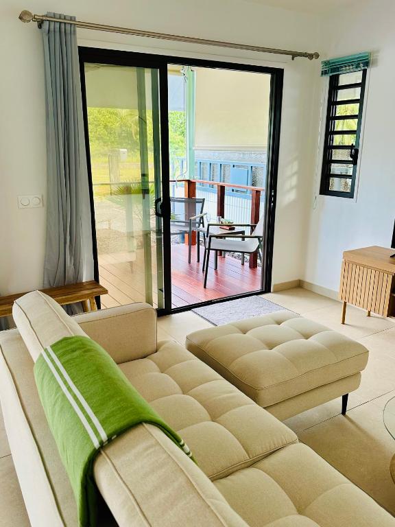 a living room with a couch and a sliding glass door at Nanua Lodge 1 green in Bora Bora