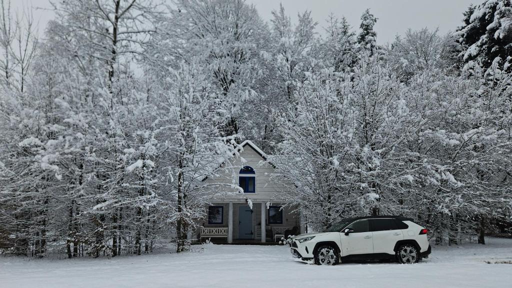 a car parked in front of a house in the snow at Biała chatka w lesie na Roztoczu in Szczebrzeszyn