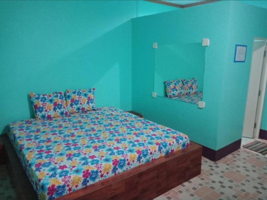 a bedroom with a bed with a blue wall at Saran Resort room 9 in Ban Khok Wat