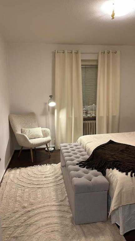 a bedroom with a bed and a chair and a window at Apartment close to city in Malmö
