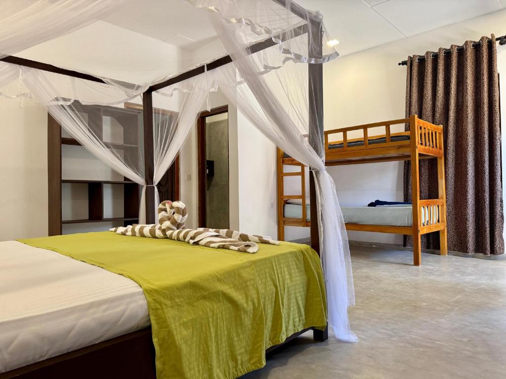 una camera con letto a baldacchino e letti a castello di kuda Bay Surf Hostel ad Arugam