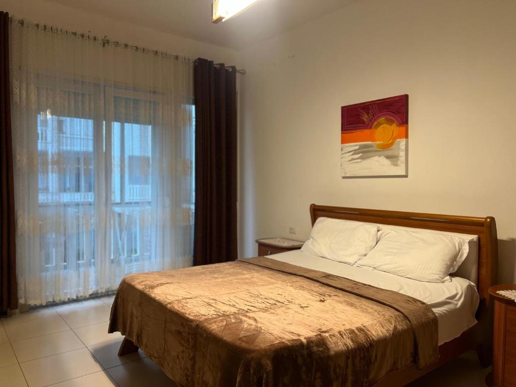 a bedroom with a bed and a large window at Blue Wave Apartment Velipoja in Velipojë