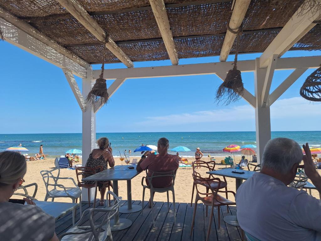 Un grupo de personas sentadas en mesas en la playa. en Het Verwende Nest, en La Mata