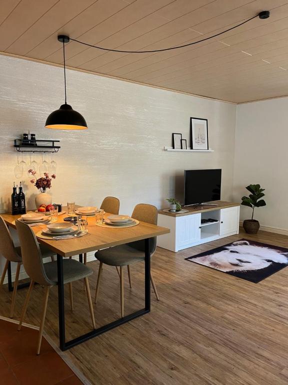 Rottal-AlpakaLodge Zeit zu Zweit im Grünen في Abtsgmünd: غرفة طعام مع طاولة وكراسي وتلفزيون