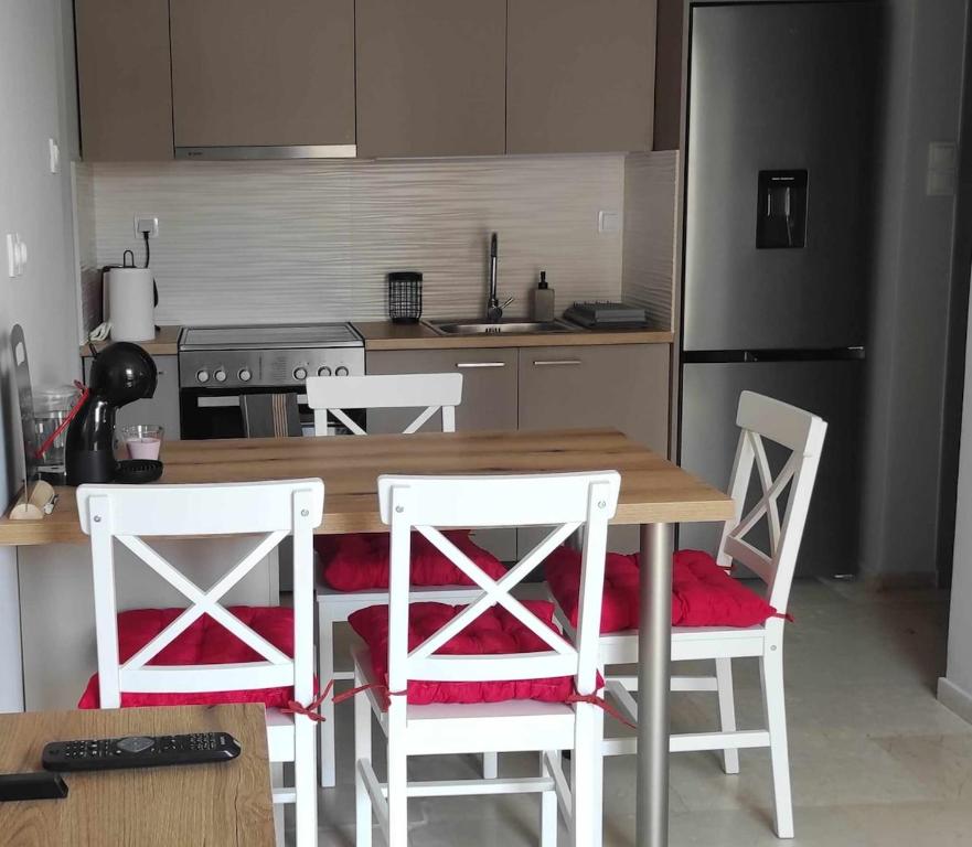 a kitchen with a wooden table and white chairs at Parastaseis City Flat Central in Patra