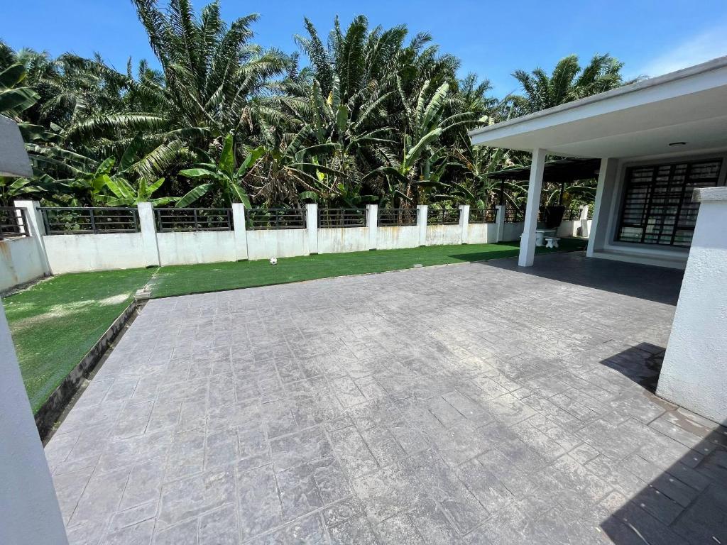 a patio in front of a house with palm trees at TF Homestay in Banting