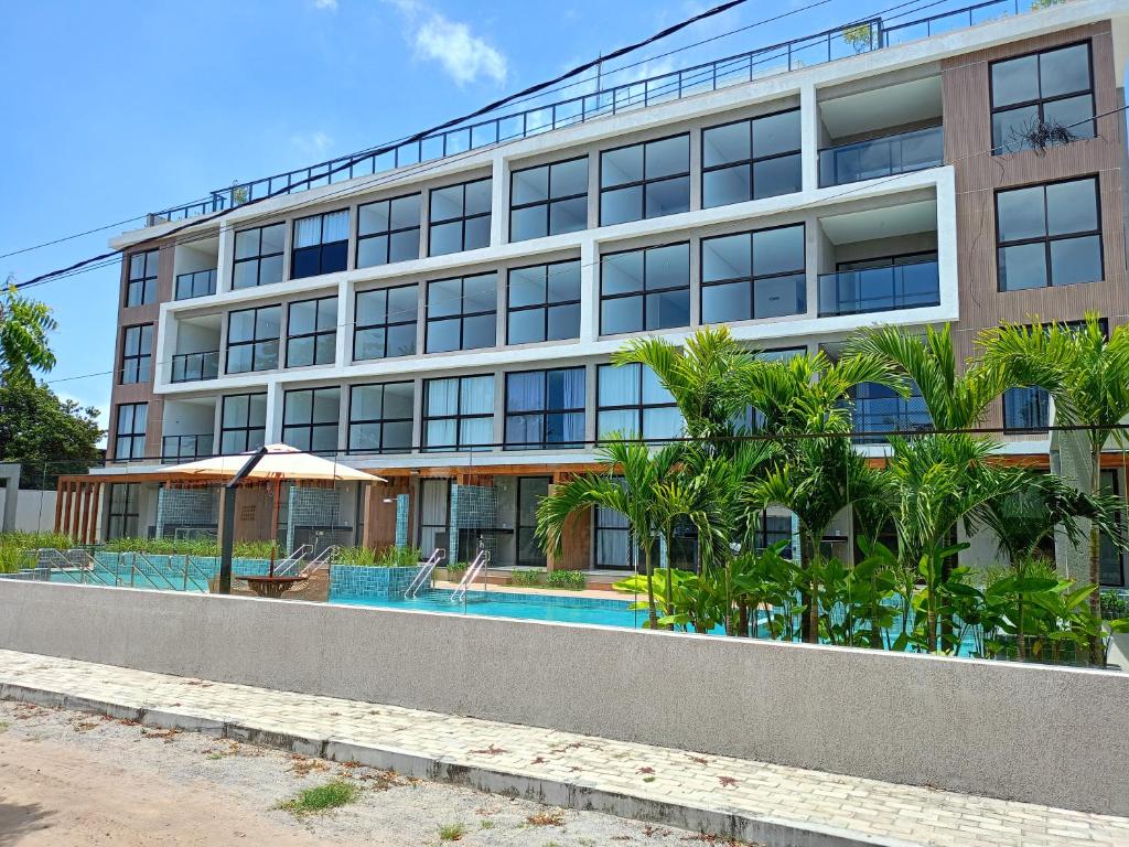 an apartment building with a swimming pool and palm trees at Aquach Beach Residence in Tamandaré