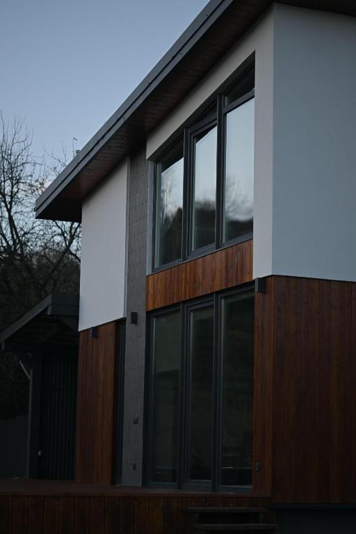 a house with glass windows on the side of it at Domivka котедж із чаном-джакузі, каміном і кіно-зоною у Cлавську in Slavske