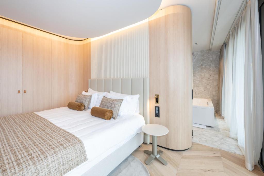 a bedroom with a large white bed and a table at Hôtel des Innovations in Marly
