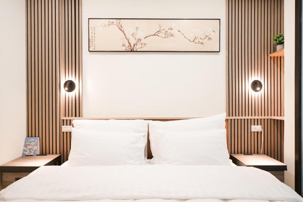 een slaapkamer met een wit bed en een ingelijste foto bij Shipu Hotel in Pu-pien