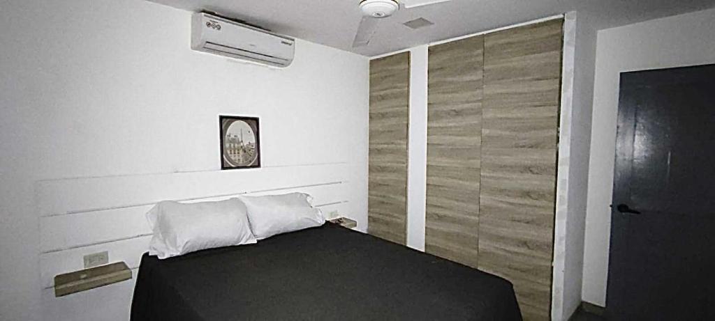 - une chambre avec un lit noir et un mur en bois dans l'établissement Casa Valentina, à Río San Juan