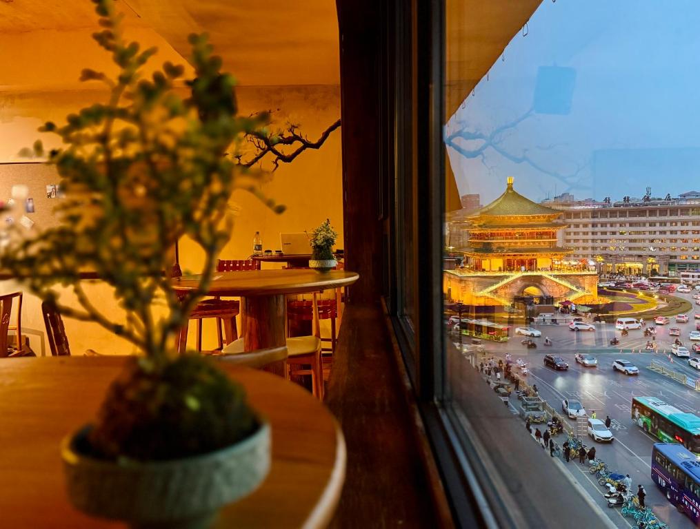 a view of a city from a window with a plant at Xi'an YOLO Guest House in Xi'an