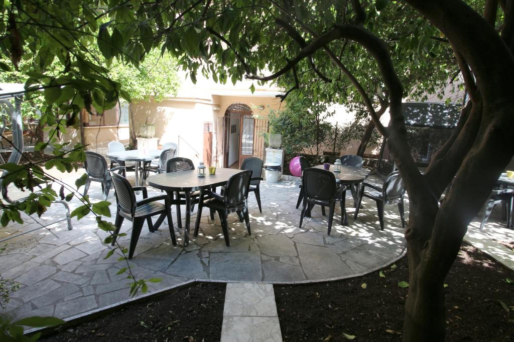 um pátio com mesas e cadeiras debaixo de uma árvore em New Generation Hostel Rome Center em Roma