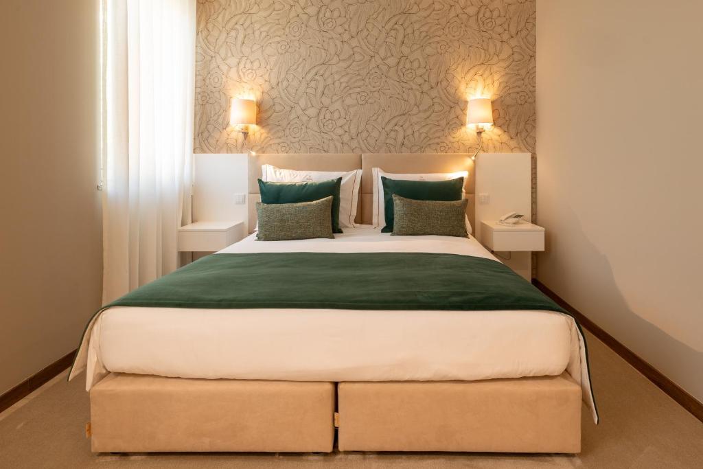 ein Schlafzimmer mit einem großen Bett mit grüner Bettwäsche und Kissen in der Unterkunft Stella Braga Aparthotel in Braga