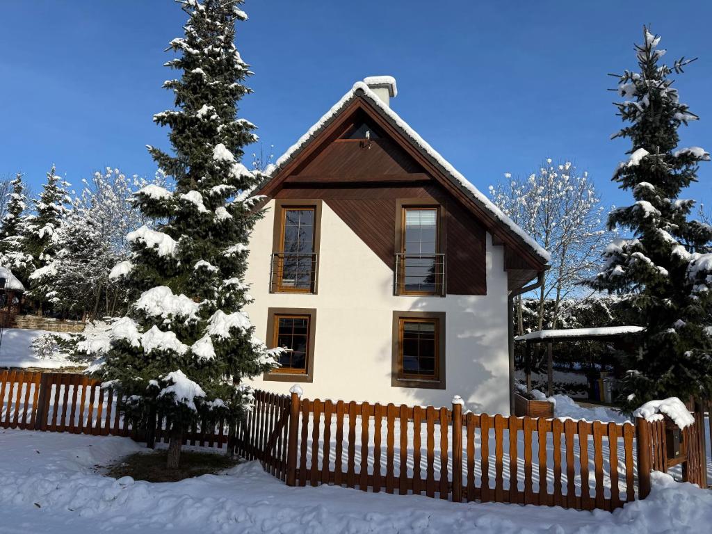 une maison avec une clôture en bois dans la neige dans l'établissement INFINITA Bodice, à Liptovský Mikuláš