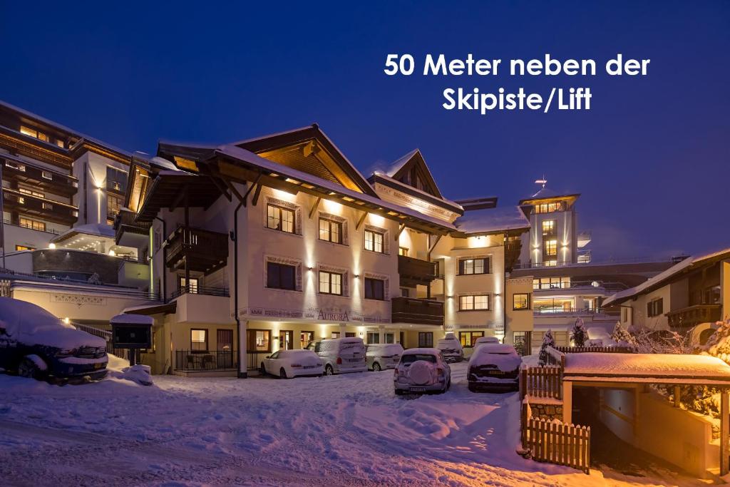 Un edificio con coches aparcados en la nieve por la noche. en Apart-Hotel Aurora Fiss, en Fiss