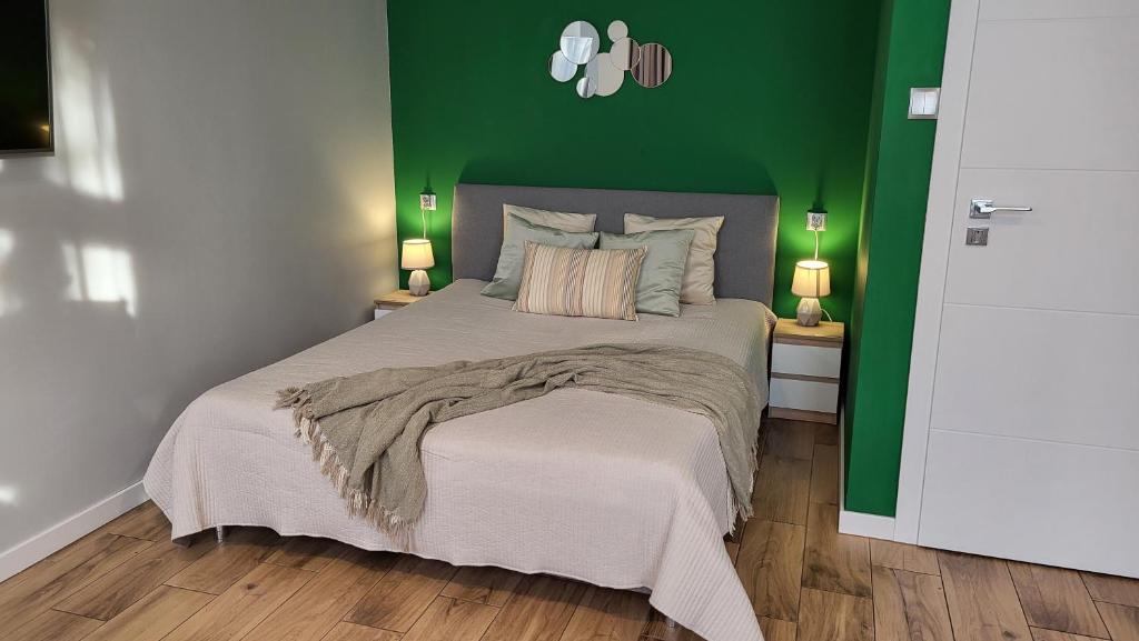 Studio - Apartamenty Parkowe في غنيزنو: غرفة نوم بسرير مع جدار أخضر