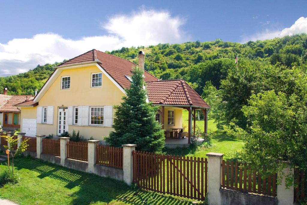 a house with a fence in front of a mountain at Bábakalács in Fony