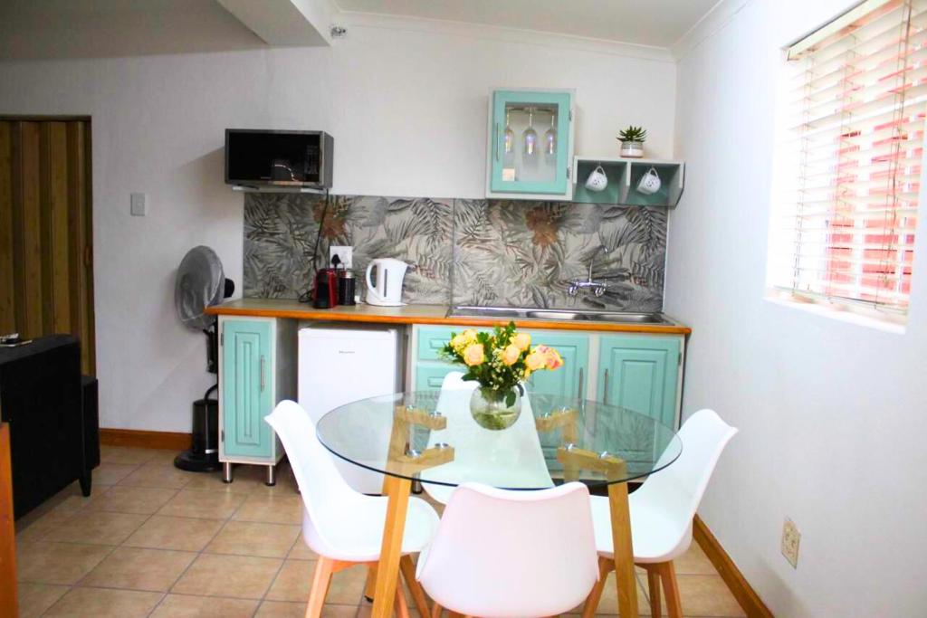 a kitchen with a glass table and white chairs at Cottage of Grace in Benoni