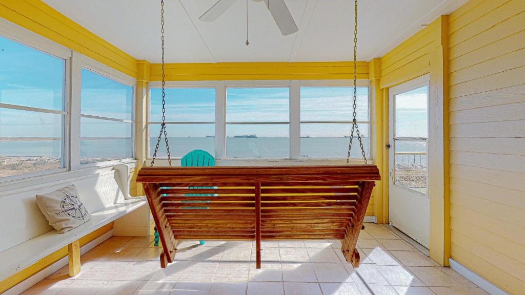 a swinging bench in a room with windows at Sun and Moon in Port Bolivar
