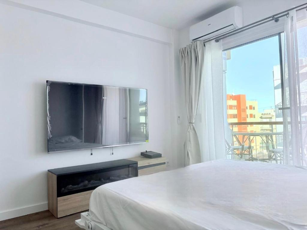 a white bedroom with a flat screen tv on the wall at Nook arenal Jávea in Platja de l'Arenal