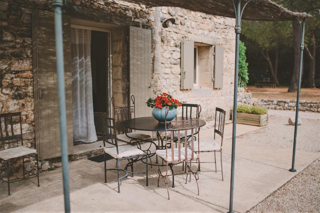 een tafel en stoelen met een vaas met bloemen op een patio bij Rodin - Mas De Rey in Arpaillargues-et-Aureillac