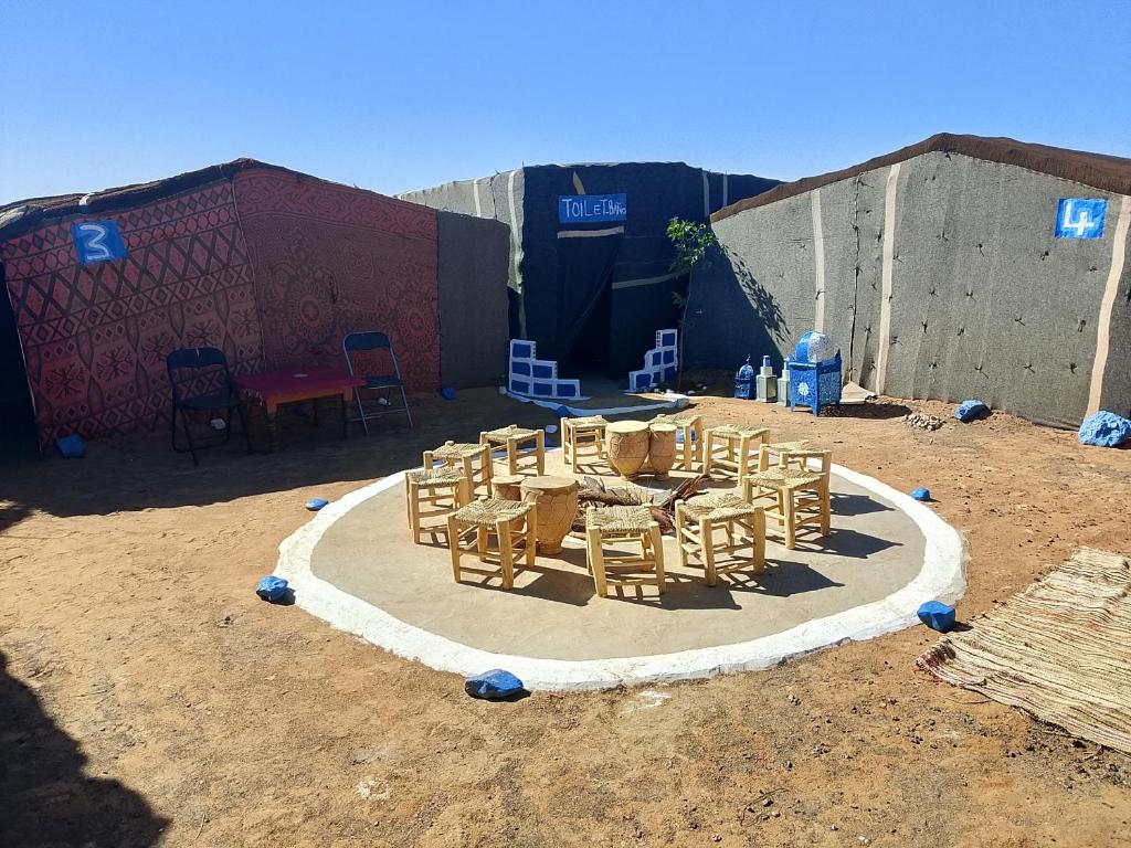 a group of tables and chairs on a circle in the dirt at Travel Oasis Merzouga Camp in Merzouga