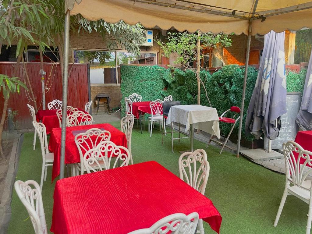 un groupe de tables et de chaises avec un tissu de table rouge dans l'établissement Essérè Mabia hôtel E-M, à Brazzaville