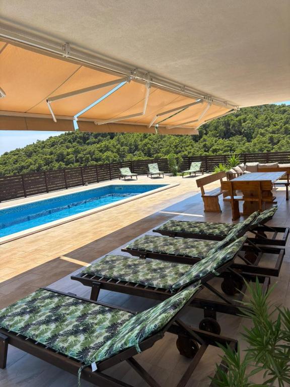eine Reihe von Liegestühlen neben einem Schwimmbecken in der Unterkunft Villa Prezzi in Novo Selo