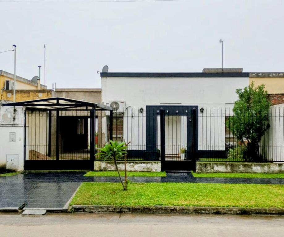 ein weißes Gebäude mit einem schwarzen Tor und einem Baum in der Unterkunft El Descanso in Concepción