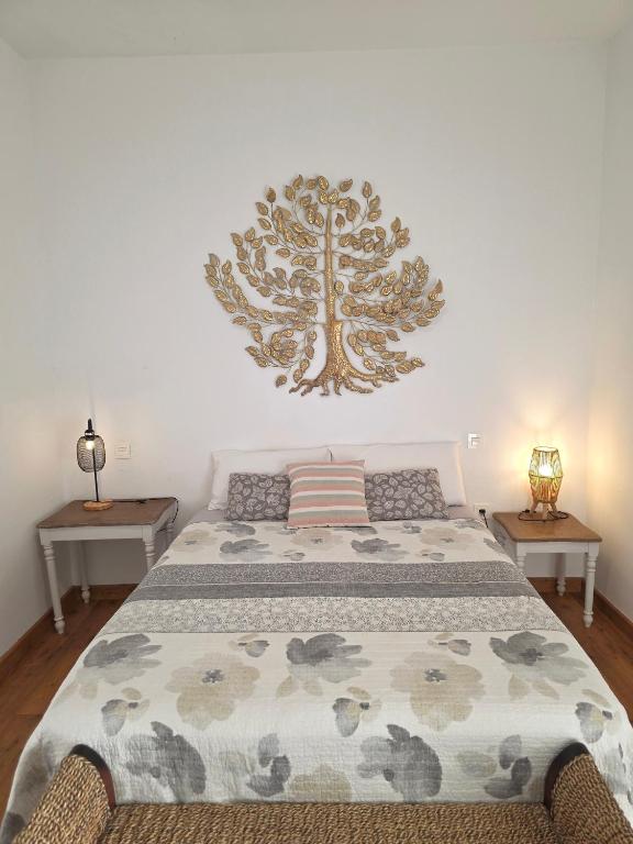 a bedroom with a bed with a tree on the wall at Alunita & Pirita Rooms - Peaceful Private Rooms with Garden, Terrace & Shared Kitchen in Nazaret