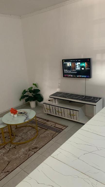 a living room with a table and a tv on a wall at Namfrey Sunny in Kiserian