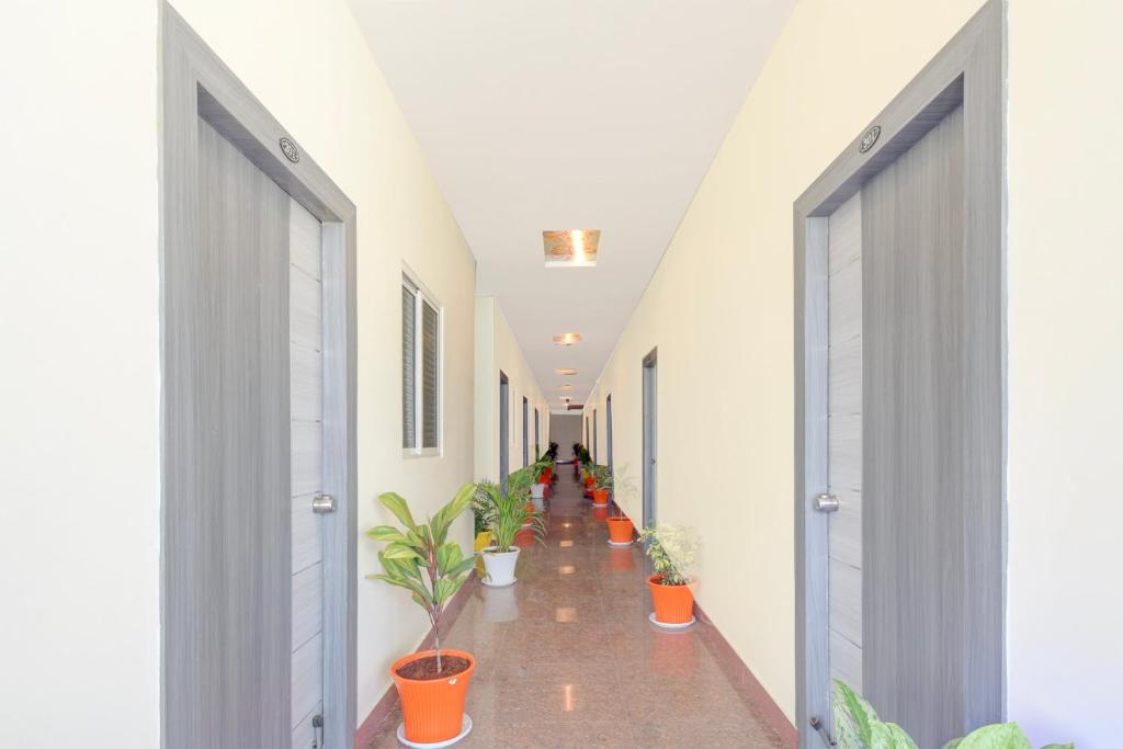 Un pasillo con plantas en macetas y una hilera de puertas. en Hotel O SRINIVASA RESIDENCY, en Pedda Ambarpet