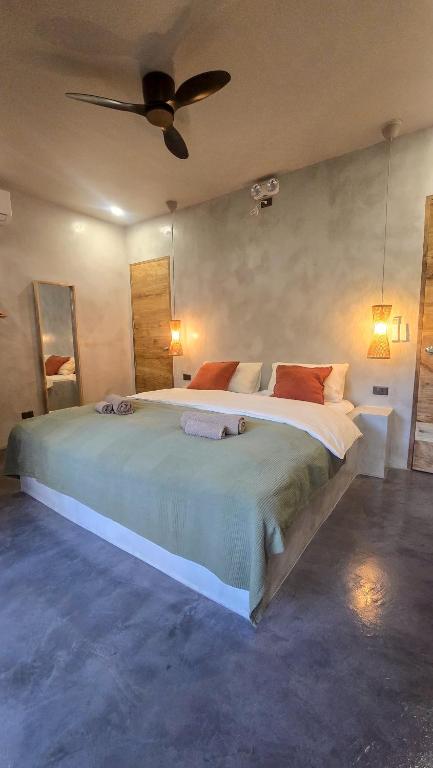 a bedroom with a large bed with a ceiling fan at Lagalag Studios in El Nido