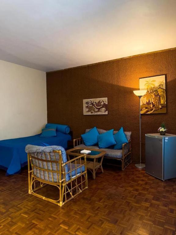 Una sala de estar con almohadas azules y un sofá. en eskimo bungalow by Fic 369, en Kadirana North