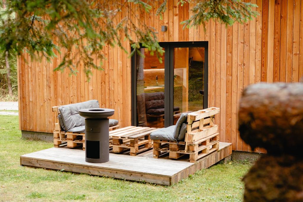 2 sillas y una mesa en una terraza frente a un edificio en Modřínka 89, en Chlum u Třeboně