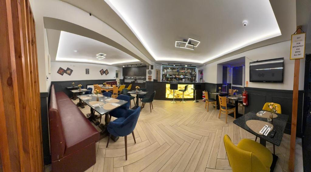 a restaurant with a bar with tables and chairs at The Gatwick White House Hotel in Horley