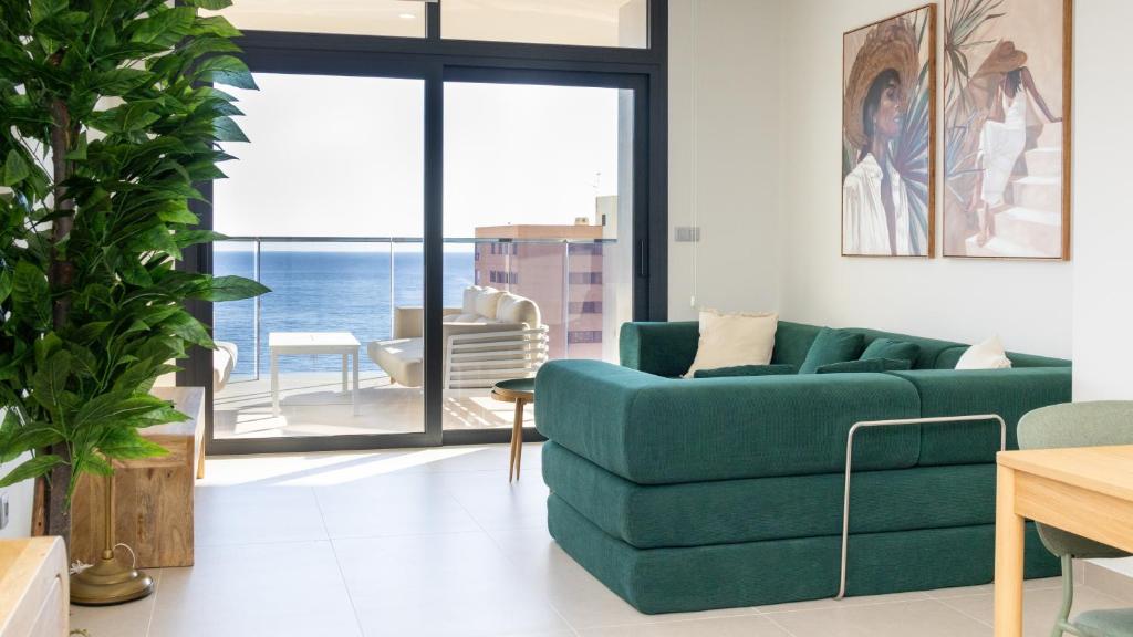 a living room with a green couch and a view of the ocean at SUNSET SAILORS vibe apartment in Benidorm
